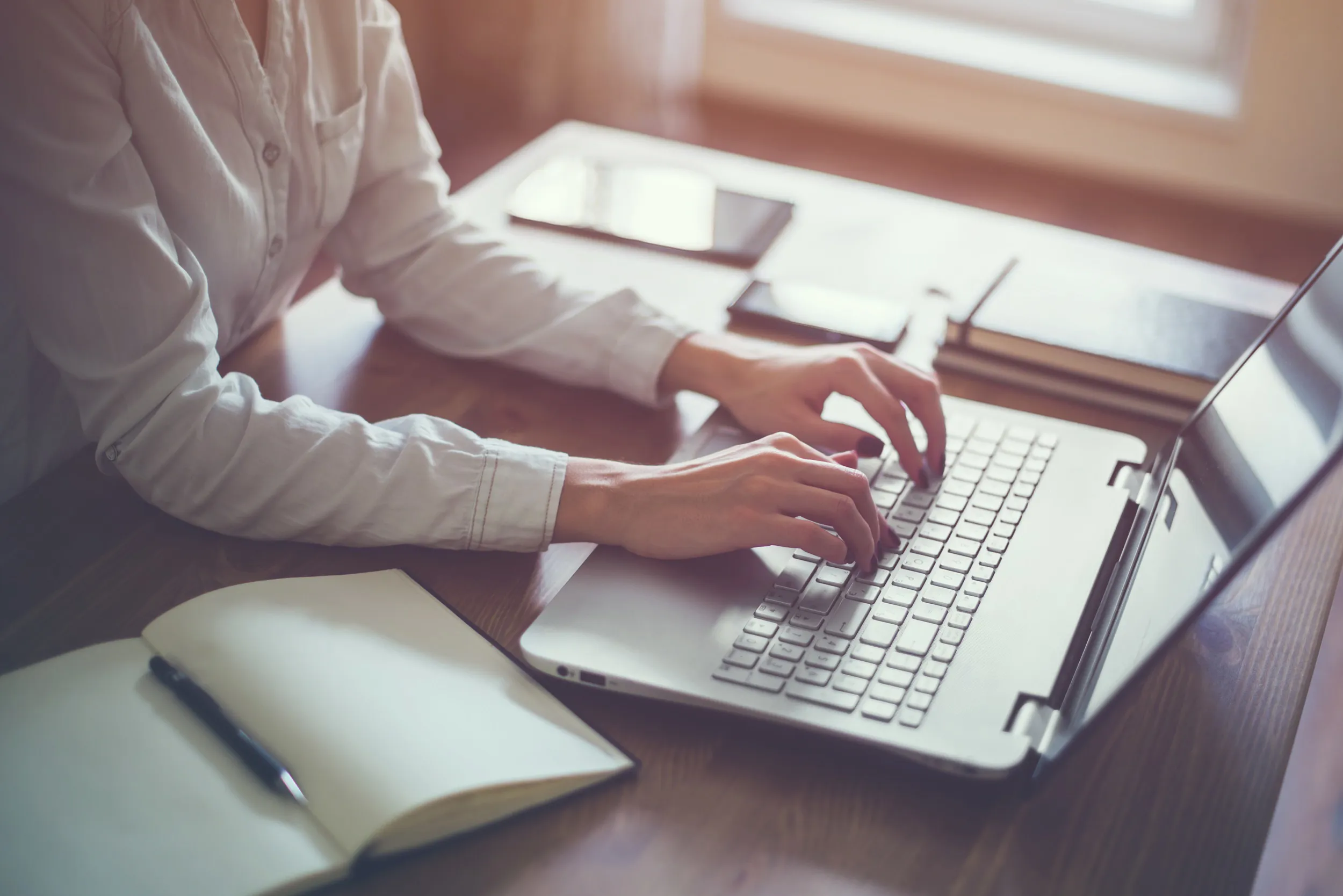 A woman focused on her laptop, typing intently in a workspace, showcasing productivity and concentration.